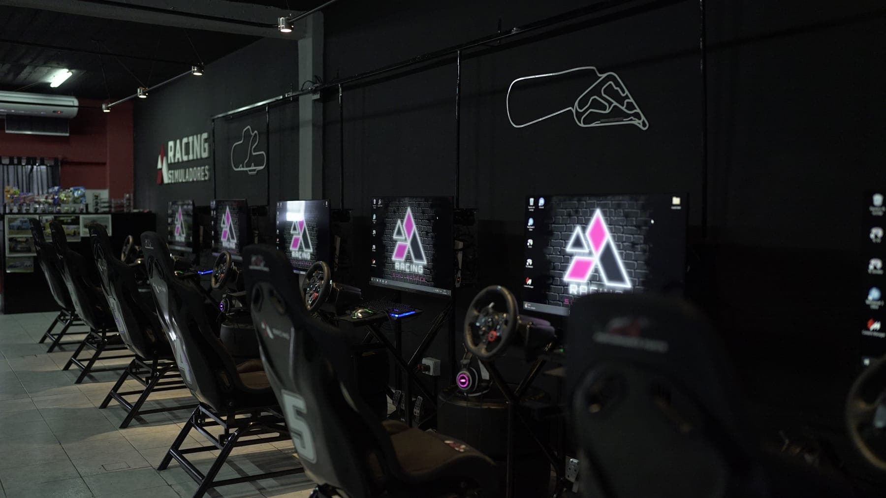 Fila de simuladores profesionales de Aracing, cada uno con volante, pedalera y pantalla propia